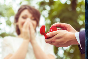 Man holding engagement ring in red box to lady