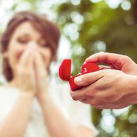 Man holding engagement ring in red box to lady